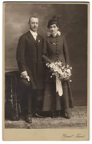 Fotografie V. Donat, Praha, Vaclavske nam 28 n., Portrait junges Paar in hübscher Kleidung mit Blumenstrauss