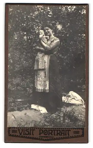 Fotografie unbekannter Fotograf und Ort, Portrait junge Mutter präsentiert ihr Kleinkind im Garten, Mutterglück