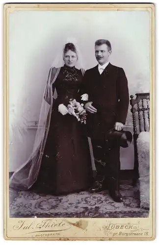 Fotografie Jul. Thiele, Lübeck, gr. Burgstr. 15, Portrait Hochzeitspaar im schwarzen Kleid und Anzug mit Zylinder