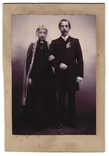 Fotografie unbekannter Fotograf und Ort, Portrait Ehepaar im schwarzen Hochzeitskleid und Anzug mit Ansteckblumen