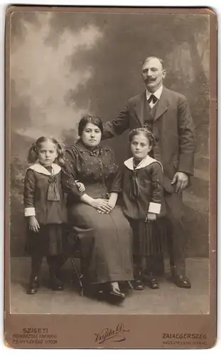 Fotografie Vajda D., Zalaegerszeg, Kossuth Lajos utca 40, Portrait bürgerliches Paar mit zwei kleinen Töchtern