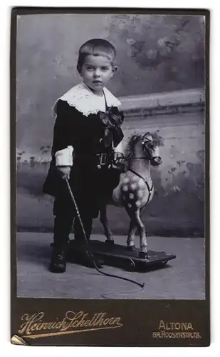Fotografie Heinrich Schellhorn, Altona, Gr. Roonstr. 73, Portrait Knabe mit Schaukelpferd im Samtkleid, Peitsche