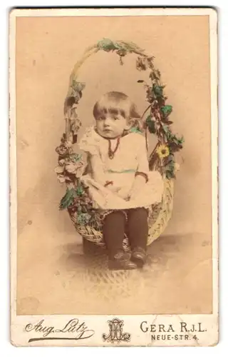 Fotografie Aug. Lutz, Gera R. j. L., Neue-Str. 4, Portrait kleines Mädchen mit Perlenkette sitzt in einem Weidenkorb