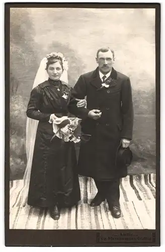 Fotografie Gg. Röckenwagner, Grafing, Portrait Eheleute im schwarzen Kleid und Anzugs Mantel