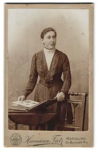 Fotografie Hermann Tietz, Hamburg, Gr. Burstah 12-14, Portrait junge Dame im Kleid mit einem Album