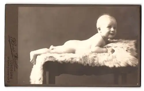 Fotografie Hans Wrede, Lüneburg, Grapengiesserstrasse 9, Portrait nackiges Baby bäuchlings auf Fell liegend