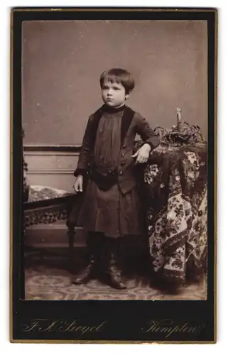 Fotografie F. X. Siegel, Kempten, Kotternerstr., Portrait hübsches Mädchen im Kleid an einem Tisch stehend