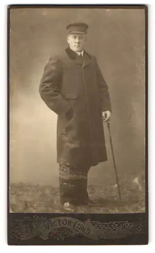 Fotografie Victor Lund, Allinge, Portrait junger Herr im Mantel mit Schirmmütze