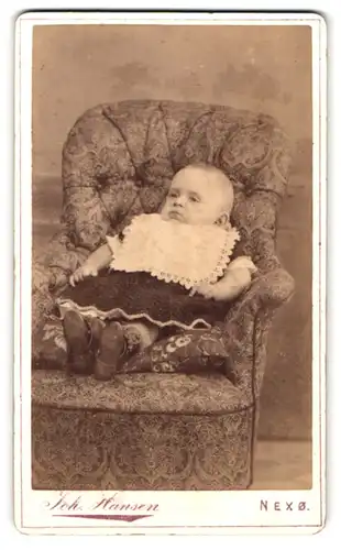 Fotografie Joh. Hansen, Nexö, Baby gemütlich in Sessel liegend