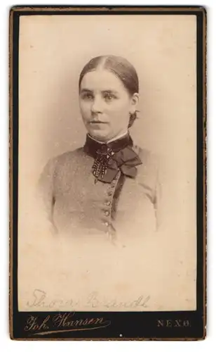 Fotografie Joh. Hansen, Nexö, Portrait von Dame mit strengem Haarknoten und mit Brosche