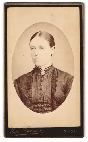 Fotografie Joh. Hansen, Nexö, Portrait von Dame mit streng zurückgebundenem Haar und Brosche