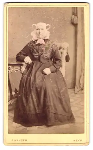 Fotografie J. Hansen, Nexö, Portrait ältere Dame im dänischen Trachtenkleid sitzend im Atelier