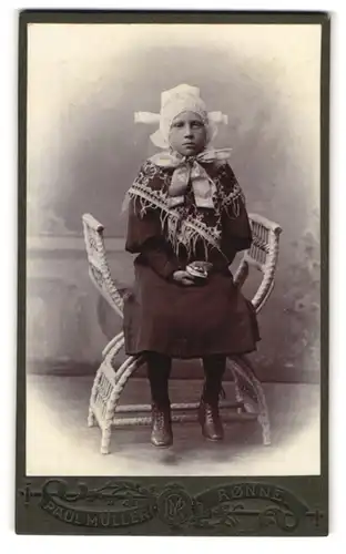 Fotografie Paul Müller, Rönne, Portrait Mädchen in dänischer Tracht mit Haube sitzend im Stuhl