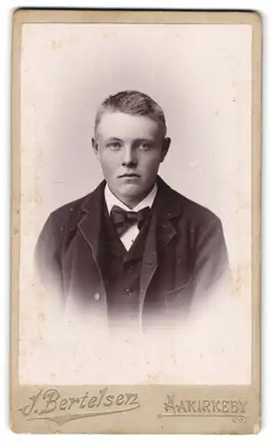 Fotografie J. Bertelsen, Aakirkeby, Portrait von jungem Mann im Anzug mit Fliege
