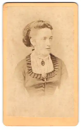 Fotografie Friedrich Berrer, Heilbronn, Bergstrasse, Dame mit zeitgenössischer Frisur in Kleid mit Brosche und Kette