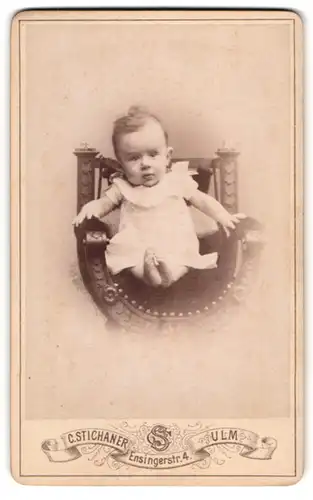Fotografie C. Stichaner, Ulm, Ensingerstrasse 4, Niedlicher Säugling in weissem Kleid im Stuhl sitzend