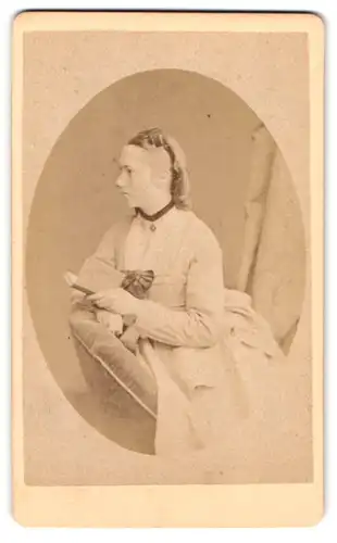 Fotografie Fr. Berrer, Heilbronn, Bergstrasse 2, Junge Dame mit zeitgenössischer Frisur mit Buch in der Hand auf Sessel