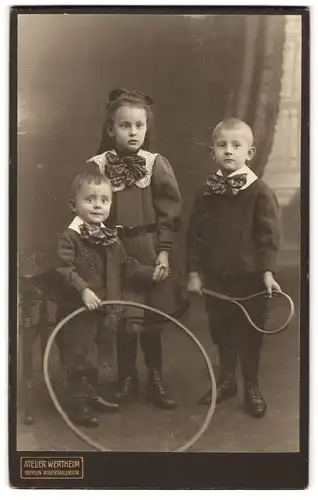 Fotografie Atelier Wertheim, Berlin, Rosenthalerstrasse, Portrait kleines Mädchen im Kleid und zwei Jungen mit Reifen