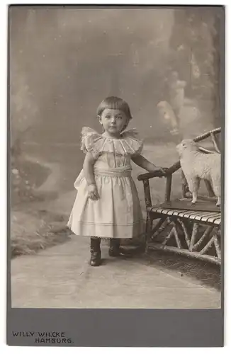 Fotografie Willy Wilcke, Hamburg, Steindamm 54-56, Portrait kleines Mädchen im Kleid mit Spielzeugschaf
