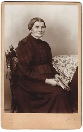 Fotografie Carl Becker, Naumburg a. S., Portrait älter Dame in hübscher Kleidung mit Buch