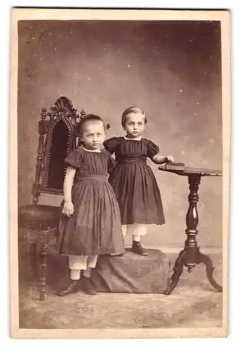 Fotografie A. Stöckel, Rönne, ved Kirken, Portrait zwei niedliche Mädchen in dunklen Kleidern posieren im Atelier