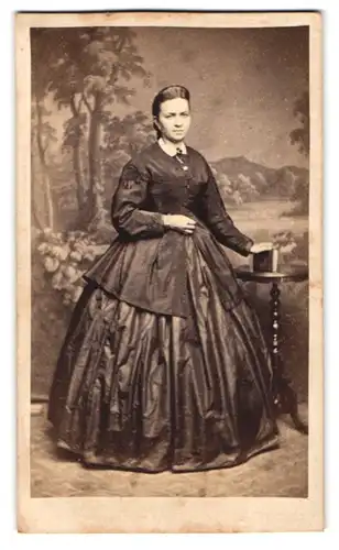 Fotografie unbekannter Fotograf und Ort, Portrait junge Frau im seidenen reifrock Kleid posiert vor einer Studiokulisse