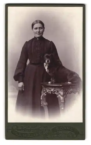 Fotografie Paul Müller, Rönne, Portrait Dame im Biedermeierkleid mit dicken Hund auf dem Tisch