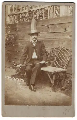 Fotografie unbekannter Fotograf und Ort, Portrait Mann Carl im Anzug mit Spazierstock und Sommerhut sitzend auf Bank