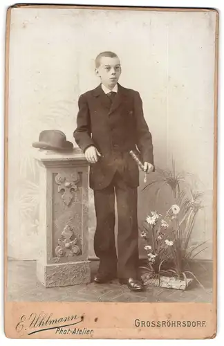 Fotografie E. Uhlmann, Grossröhrsdorf, junger Knabe im Anzug mit Bibel und Hut auf einer Säule