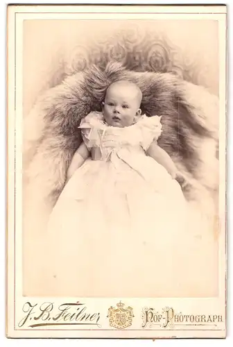Fotografie J. B. Feilner, Hannover, Georgstrasse 25, Säugling im weissen Kleidchen auf Fell