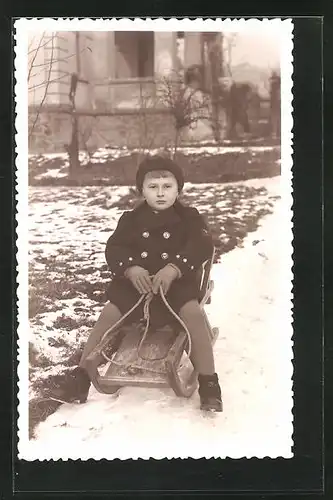AK frecher Bube auf einem Schlitten im schneebedeckten Garten