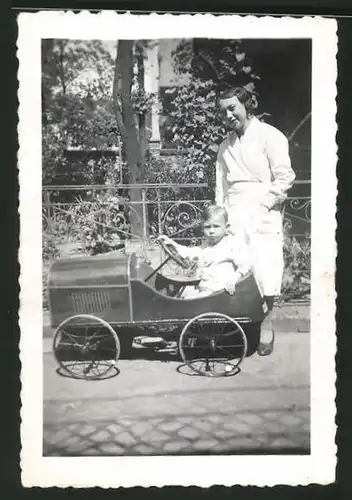 Fotografie Knabe sitzt im Tretauto - Seifenkiste