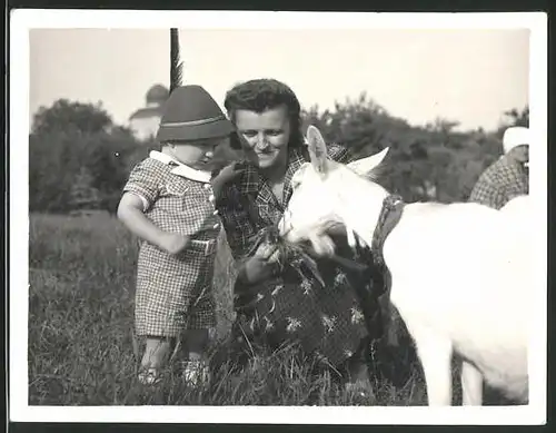 Fotografie Mutter & Sohn füttern eine Ziege