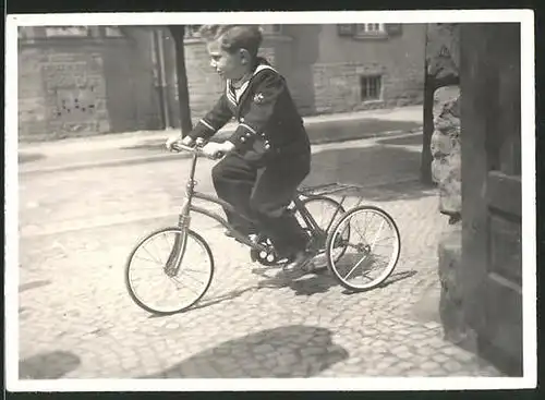 Fotografie Knabe in Marineuniform fährt auf Dreirad