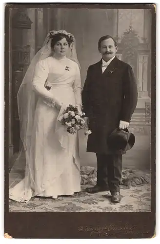 Fotografie B. Wendsche, Ingolstadt, Milchstrasse 14, Portrait junges Paar in Hochzeitskleidung mit Blumenstrauss