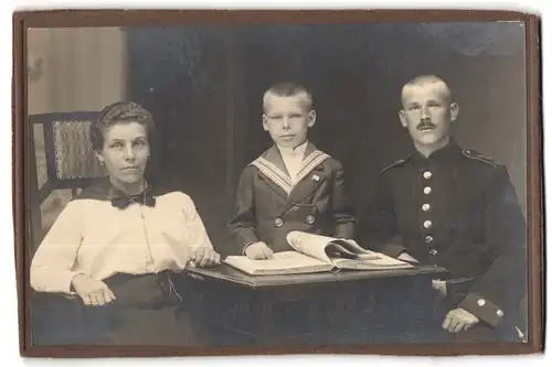 Fotografie unbekannter Fotograf und Ort, Portrait Soldat in Uniform mit Frau und Sohn am Tisch