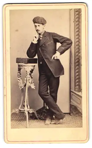 Fotografie unbekannter Fotograf und Ort, Portrait Herr im Anzug mit Barett und Malerkoffer posiert im Atelier
