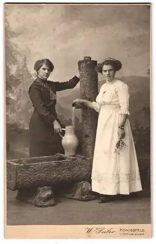 Fotografie W. Seiler, Königsfeld i. Schwarzwald, Portrait zwei Damen in Kleider an einem Brunnen mit Lametta Wasser