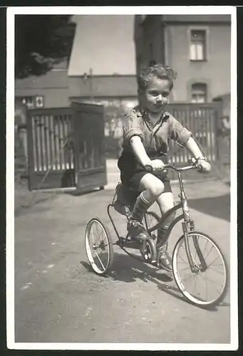 Fotografie Knabe fährt auf Dreirad