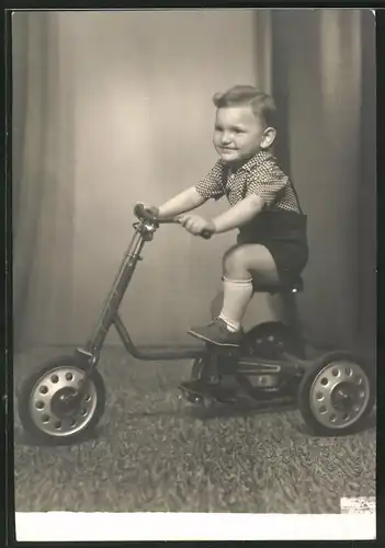 Fotografie stolzer Knabe mit seinem Dreirad