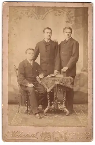 Fotografie E. Uhlenhut, Coburg, Am Albertplatz, Portrait drei junge Herren im Anzug am Tisch