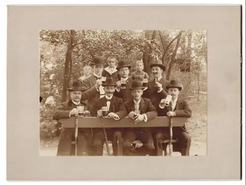 Fotografie unbekannter Fotograf und Ort, Herrenrund ein Anzügen mit Schwarzbier Krügen in der Hand