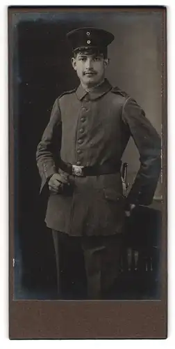 Fotografie unbekannter Fotograf und Ort, junger Soldat in Feldgrau Uniform Rgt. 132 mit Bajonett und Zigarre