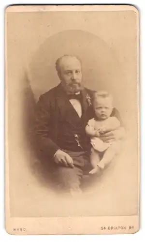 Fotografie Ward, London, 54, Brixton Rd., Portrait bürgerlicher Herr mit Kleinkind auf dem Schoss