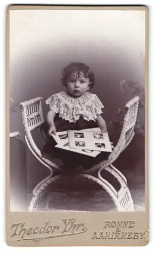 Fotografie Theodor Yhr, Rönne, Storetorv, Portrait süsses kleines Mädchen hält Fotos in den Händen
