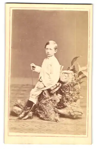 Fotografie C. J. Ophoven, Lippstadt, Portrait blonder frecher Bube auf einem Stein sitzend