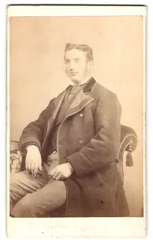Fotografie W. Sutherland, Sunderland, Frederick Street, Portrait stattlicher Mann im Mantel am Tisch sitzend