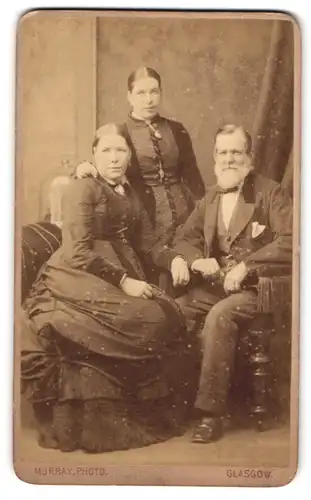 Fotografie Murray, Glasgow, 74 Broomielaw St., Portrait zwei hübsche Damen mit einem elegant gekleideten Herrn