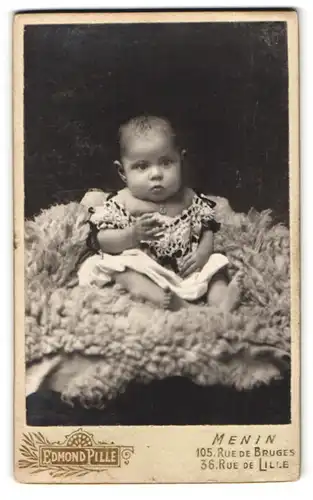 Fotografie E. Pille-Tyberghein, Menin, Rue de Bruges, 105, Portrait süsses Kleinkind im Kleid sitzt auf Fell