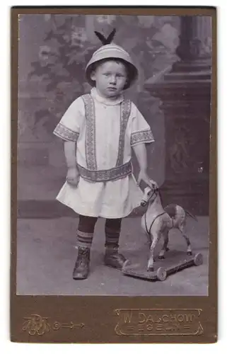 Fotografie W. Dalchow, Egeln, Portrait kleines Kind im Kleid mit Holzpferd